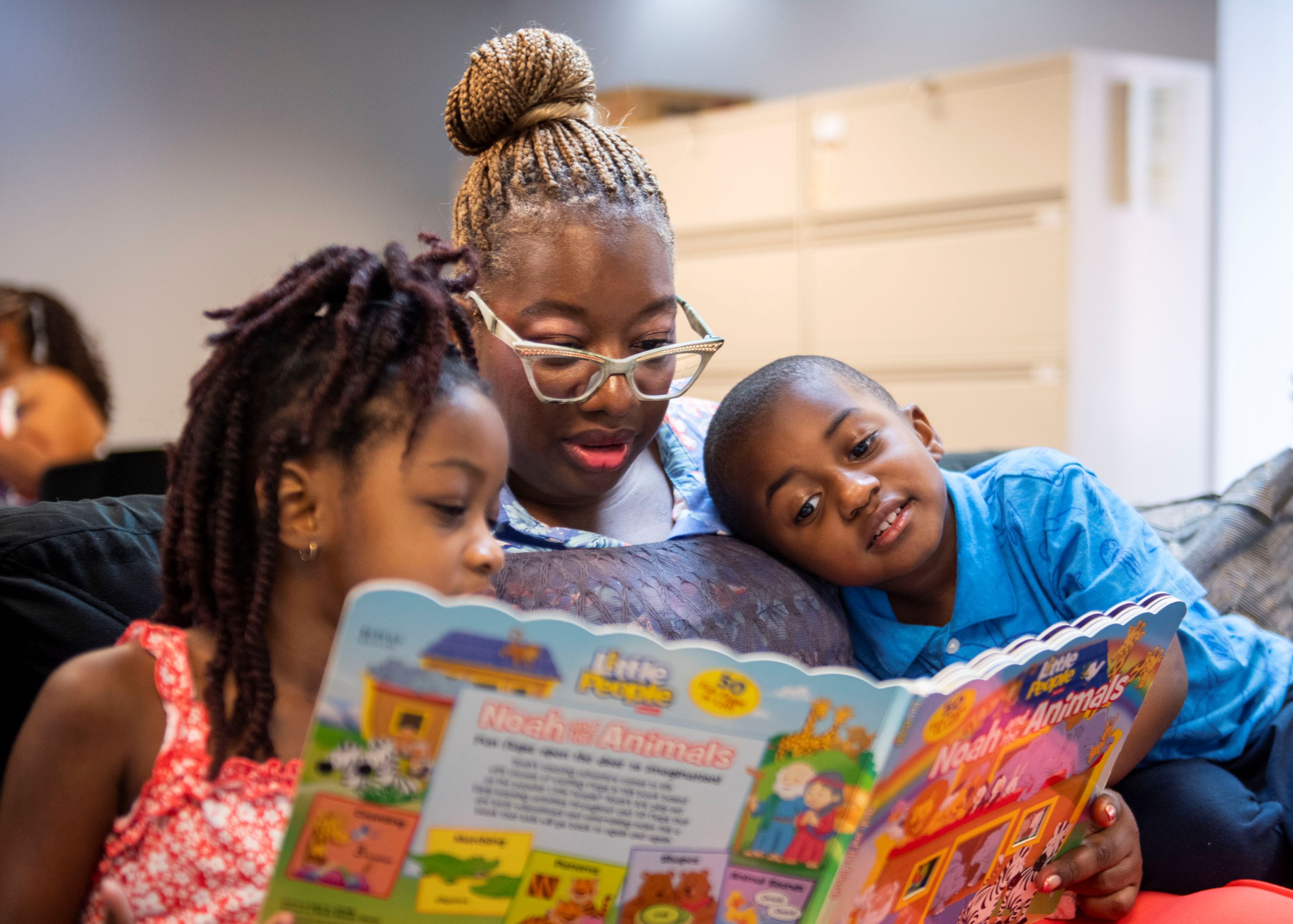 Mom reading a book to her kids.