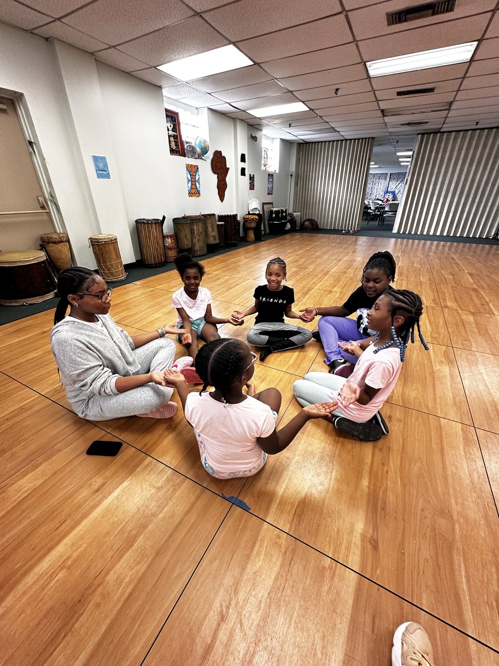 Children and their teaching sitting in a circle on the floor.